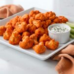 cauliflower bites with buffalo tossed and serving with celery sticks